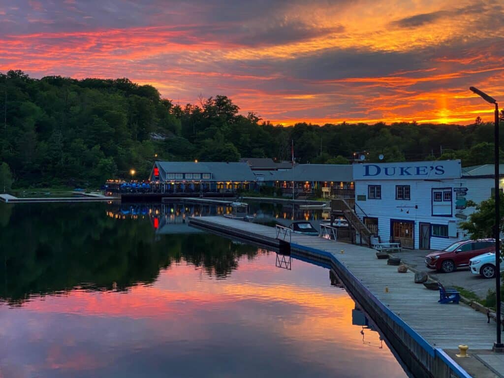Sunset over Muskoka cottage with waterfront view and dock.