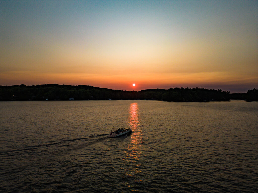 Drone shot of a boat on the Muskoka Lakes waterfront at sunset, used as the hero image for the 2025 real estate market report.