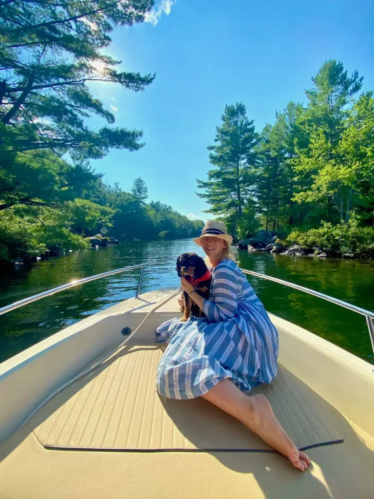 A woman and a dog on a boat navigating the narrows near Helen Island entering Lake Joseph Muskoka.