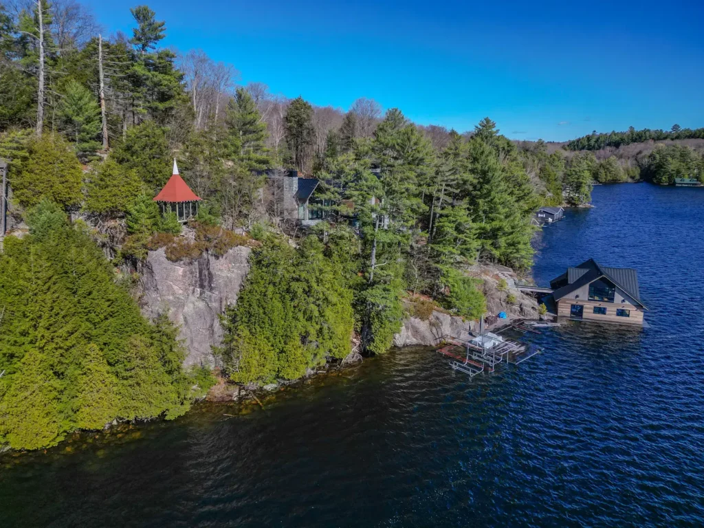 A modern luxury cottage and two-storey boathouse built onto a steep granite cliff on Little Lake Joseph.